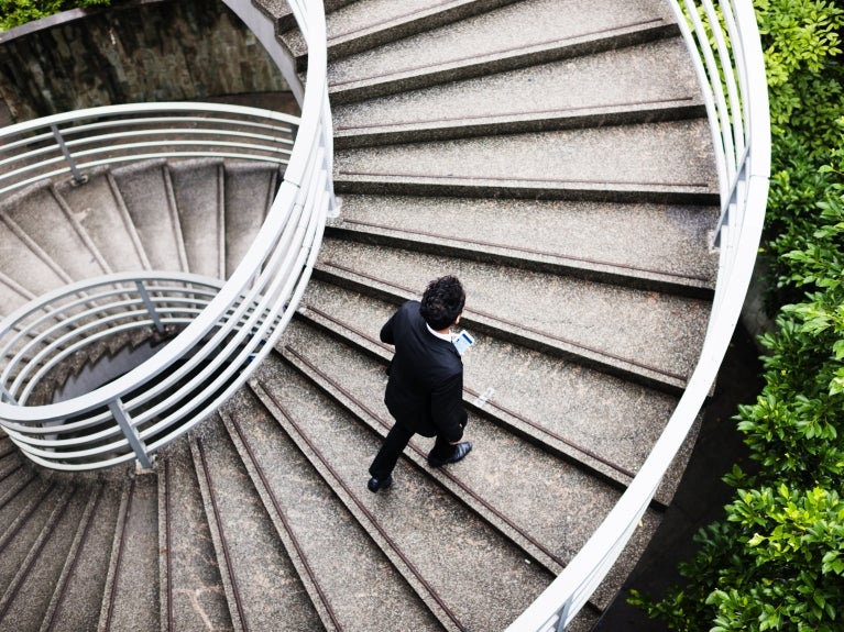 man walking up spiral concrete staircase 