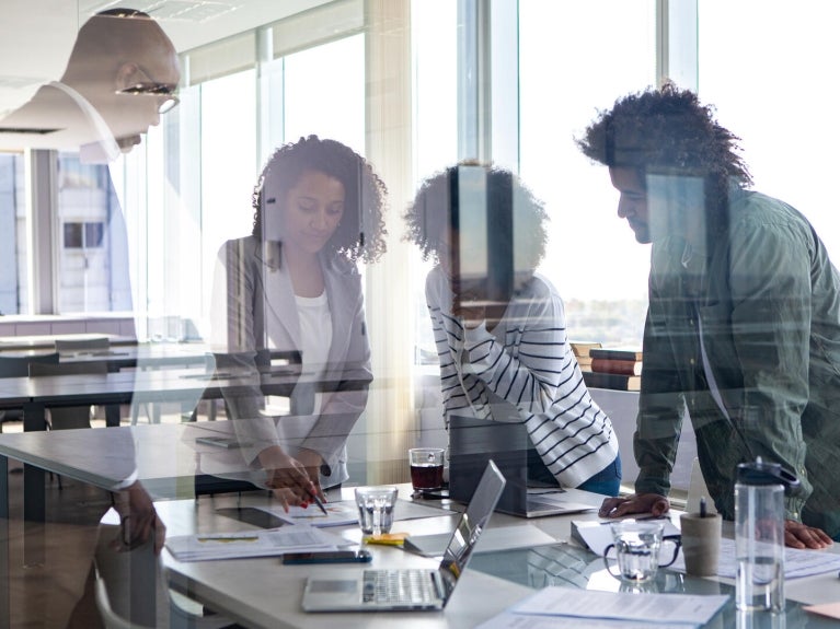 Group of people standing over a table in a conference room.