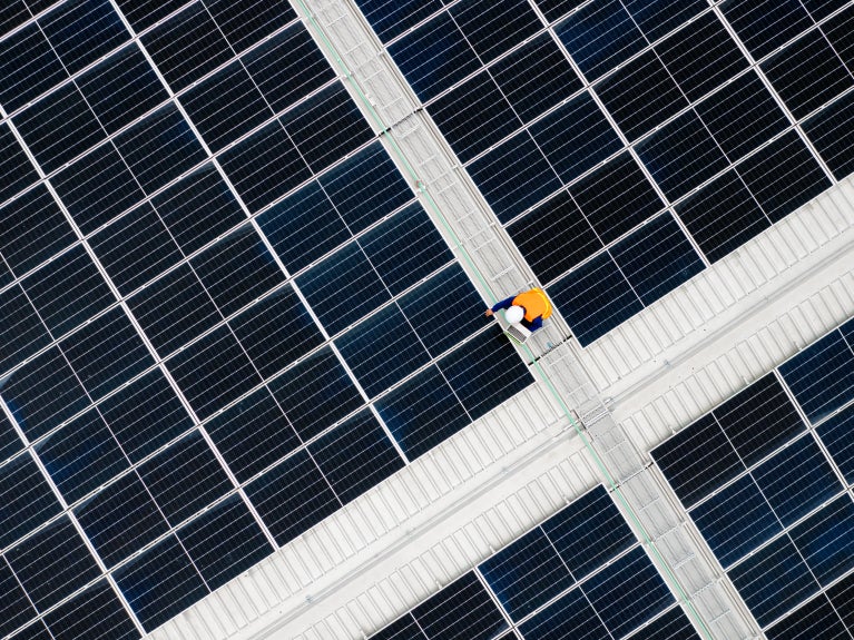 Worker standing among solar panels