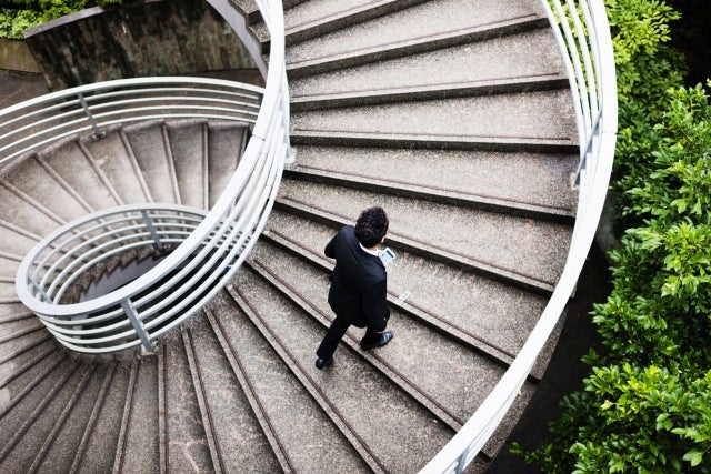 man walking up spiral concrete staircase 