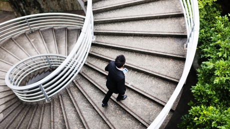 man walking up spiral concrete staircase 