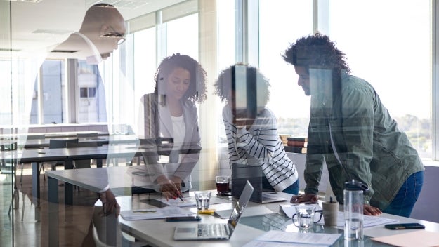 Group of people standing over a table in a conference room.