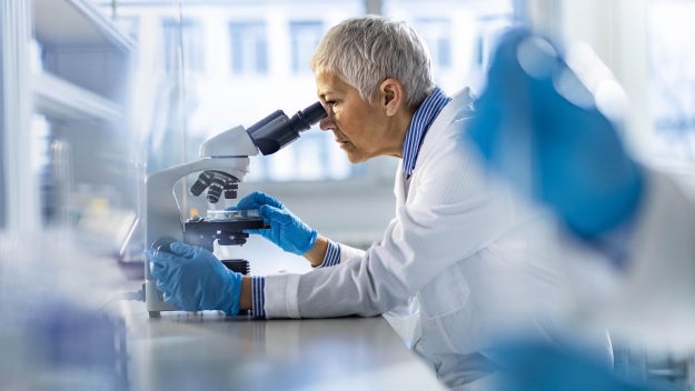 Healthcare worker looking through a microscope.